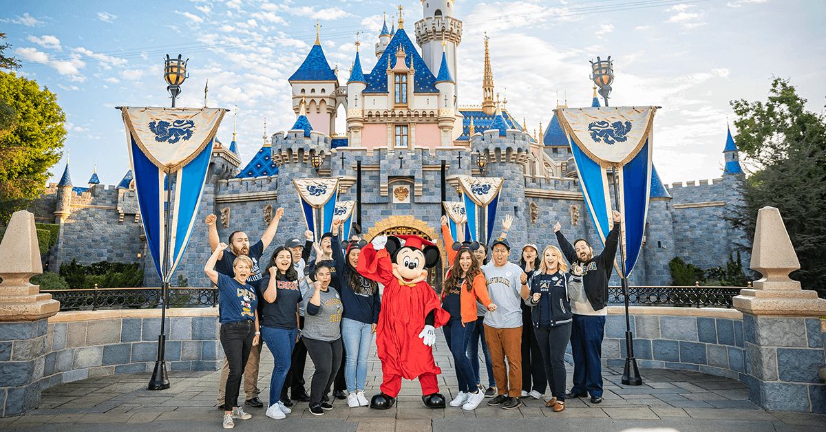 college students and mickey mouse wearing a graduation gown at disneyland 