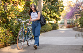 student walking a bike on path