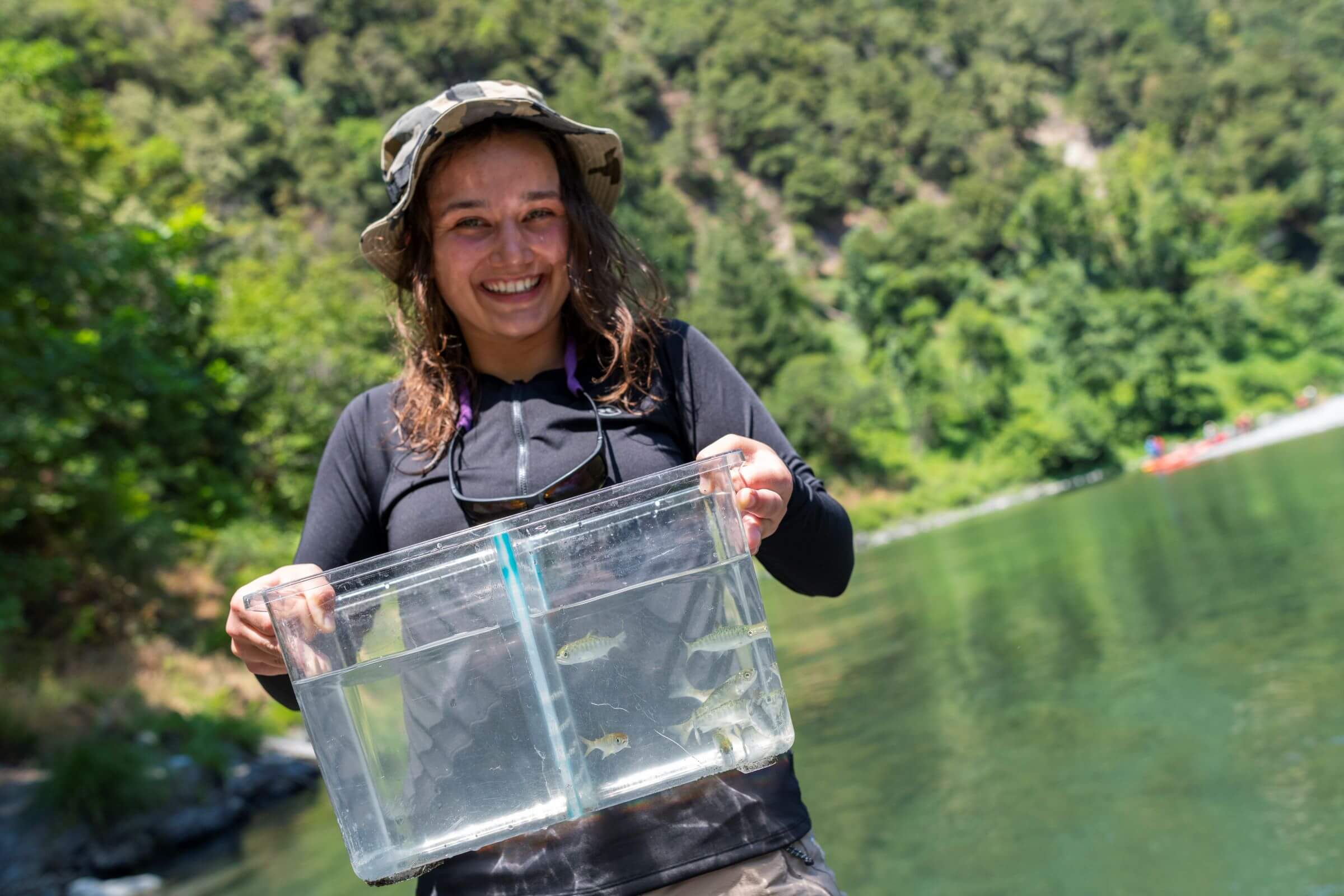 A Cal Poly Humboldt student holding a bucket of fish.