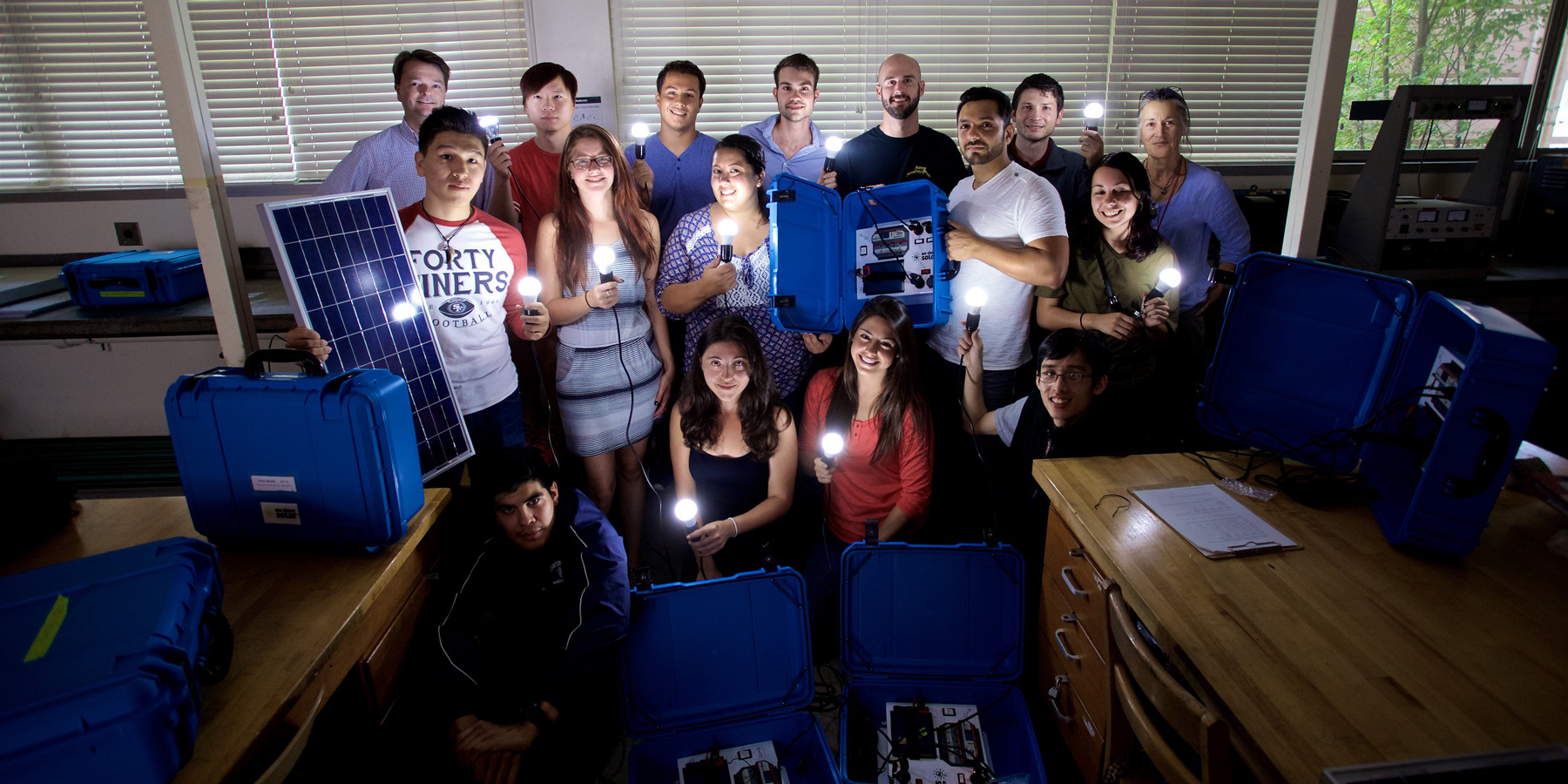 a group of college student holding solar powered lightbulbs