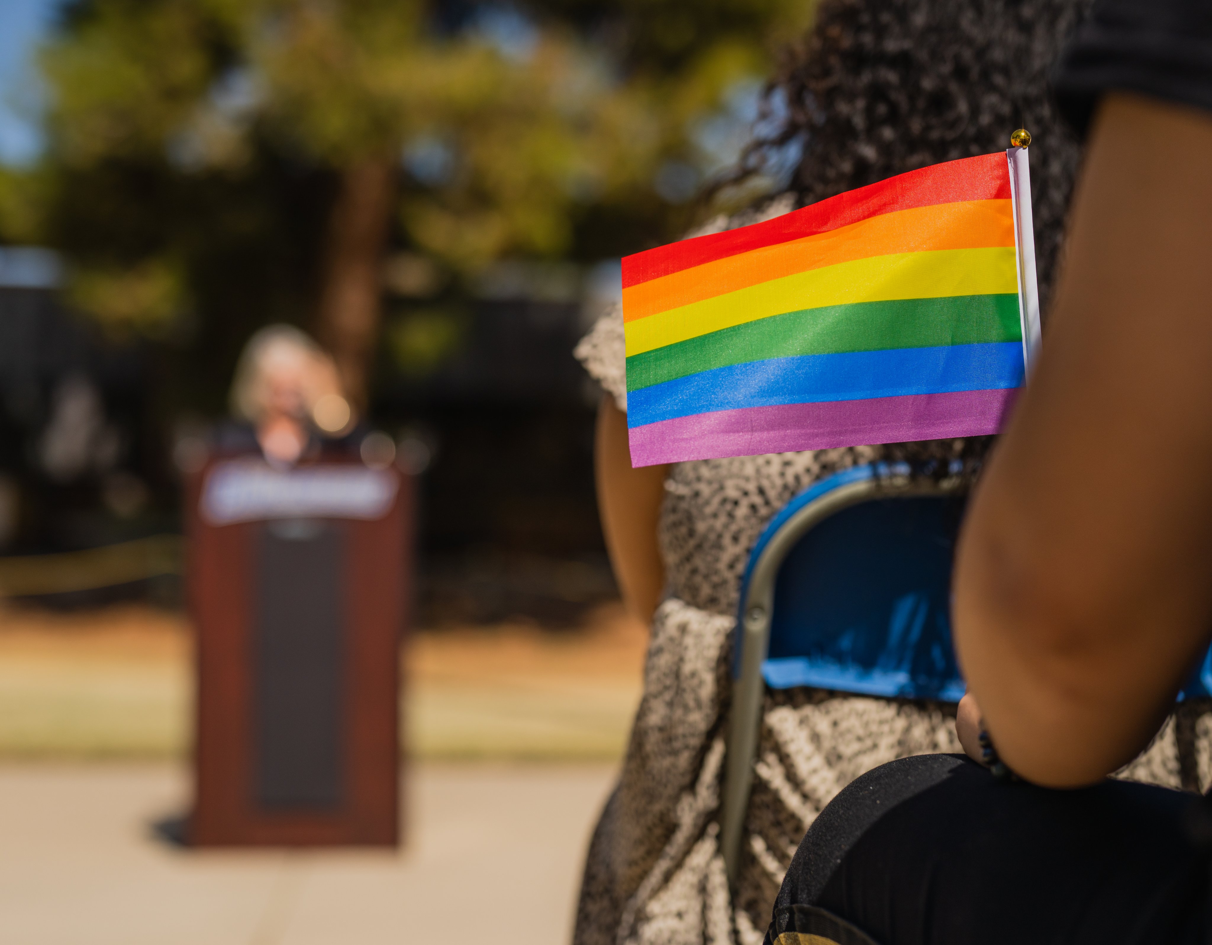 person sitting in a chair holding rainbow flag