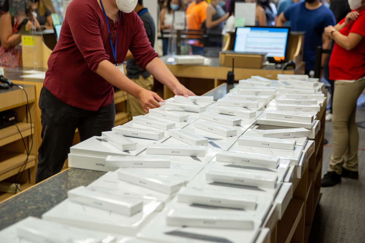 person in college bookstore arranges stacks of new technology bundles available for students