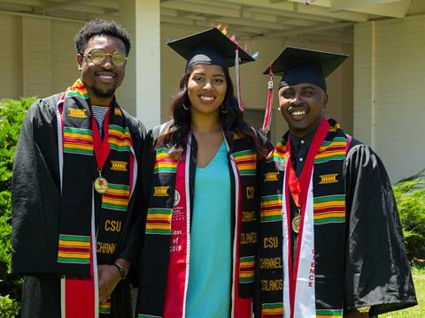 three new college graduates dressed in commencement attire