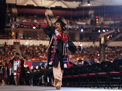 Latinx student walking across stage during CSU graduation ceremony.