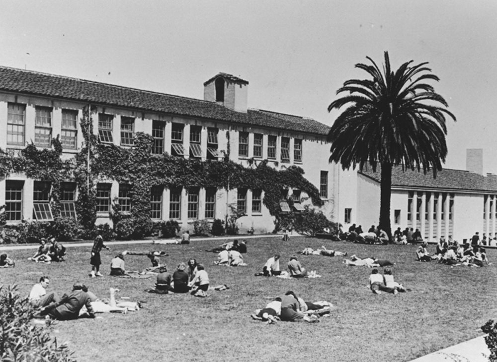 Students lounging on the grass in front of a school building