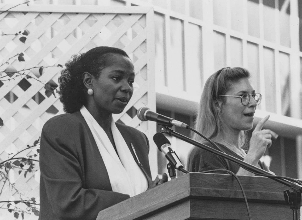 Two women speaking and presenting in front of a group