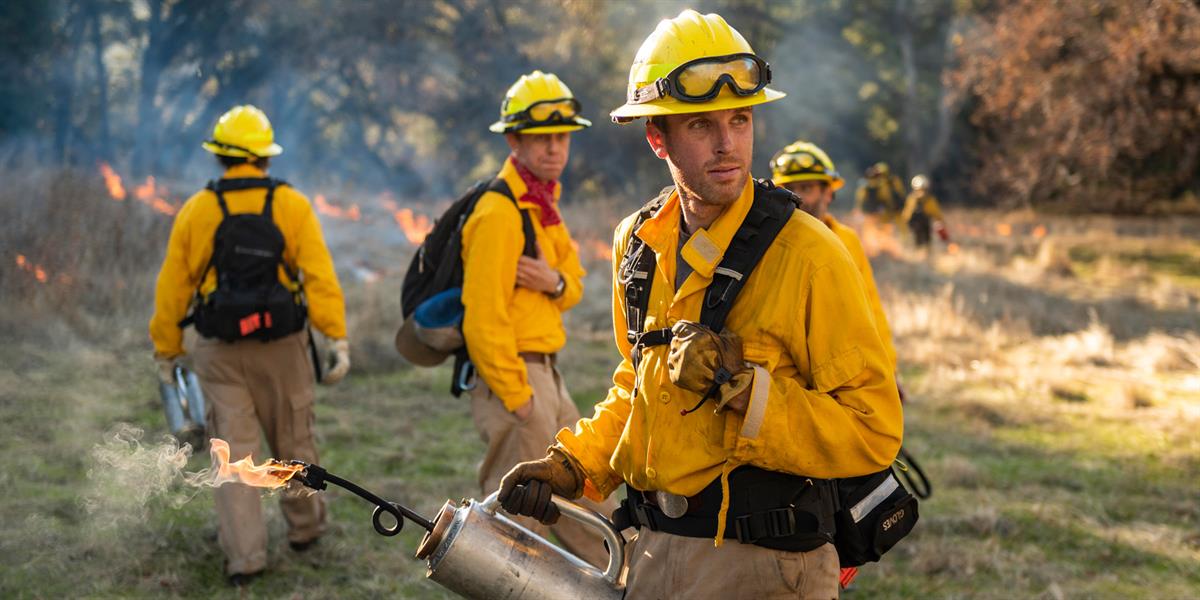 men in the field wearing wildfire gear preparing a controlled burn