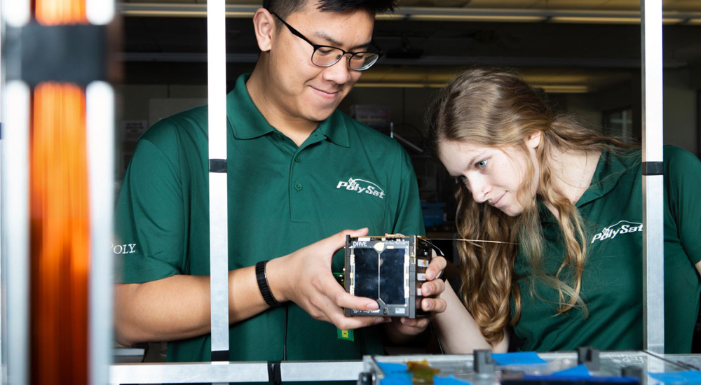 Two students study a piece of equipment.