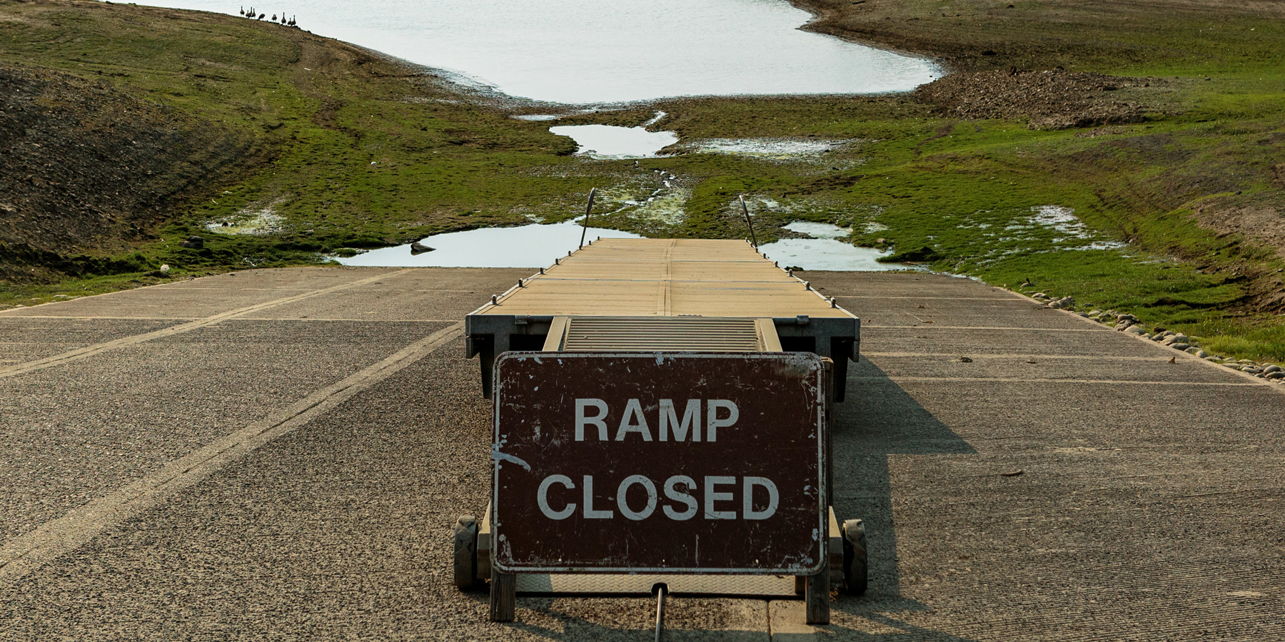 A ramp closed sign sits at the foot of a boat ramp.