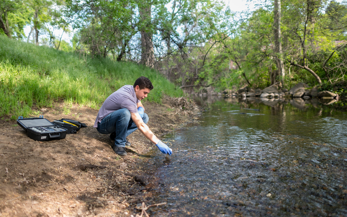 Chico State student ollects a water sample from Big Chico Creek.