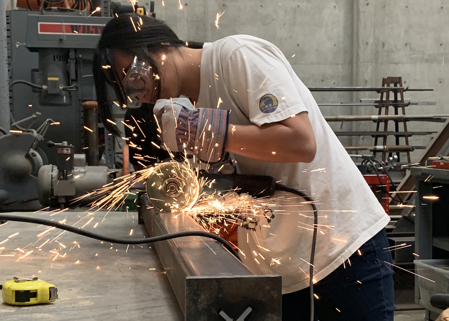 Undergraduate student Lilliann Lai dissects the student built buckling restrained brace with a grinder and cutting wheel, so the ARCE 372 Steel Design Lab class can investigate how the inner steel core performed during the full-scale frame test.