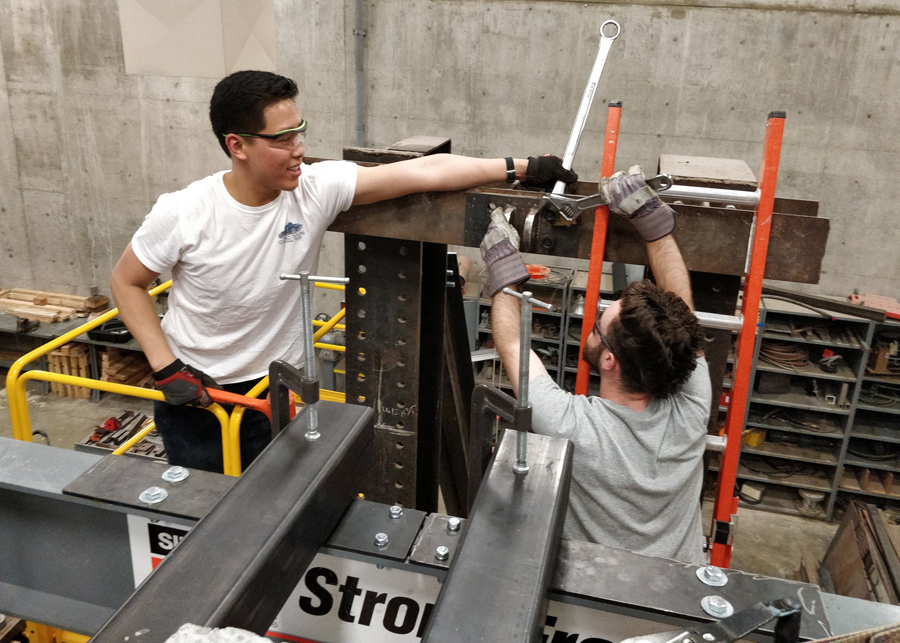 Graduate students Jerry Luong and Rory de Sevilla install a custom built bracket that will support a hydraulic jack and be used to simulate earthquake forces on a full-scale concrete wall as part of their masters research under Professor Michael Deigert.