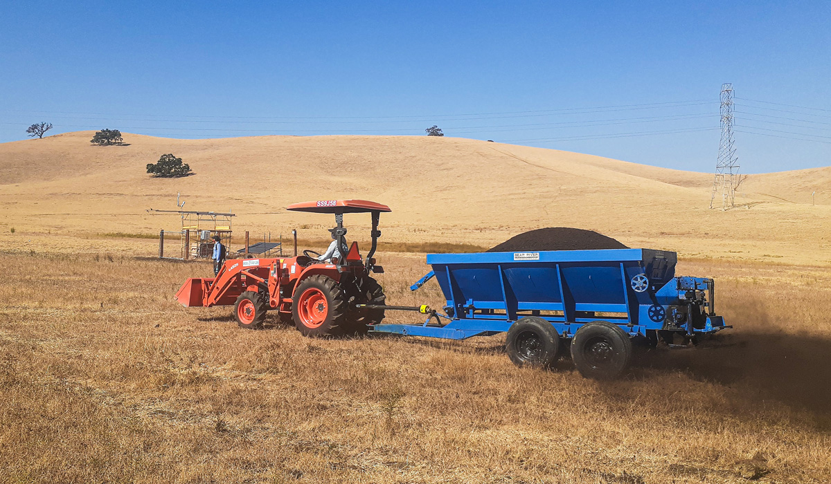 A tractor spreads compost across rangelands.