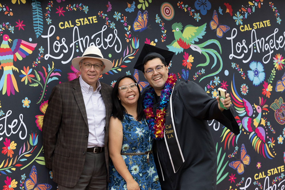 graduating student and family in front of colorful sign 