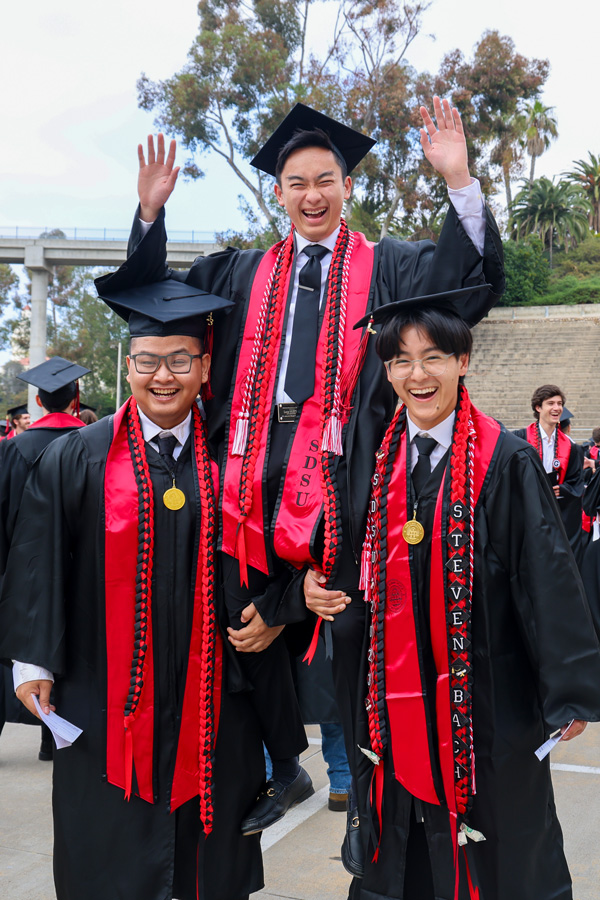 two graduating students holding another on their shoulders