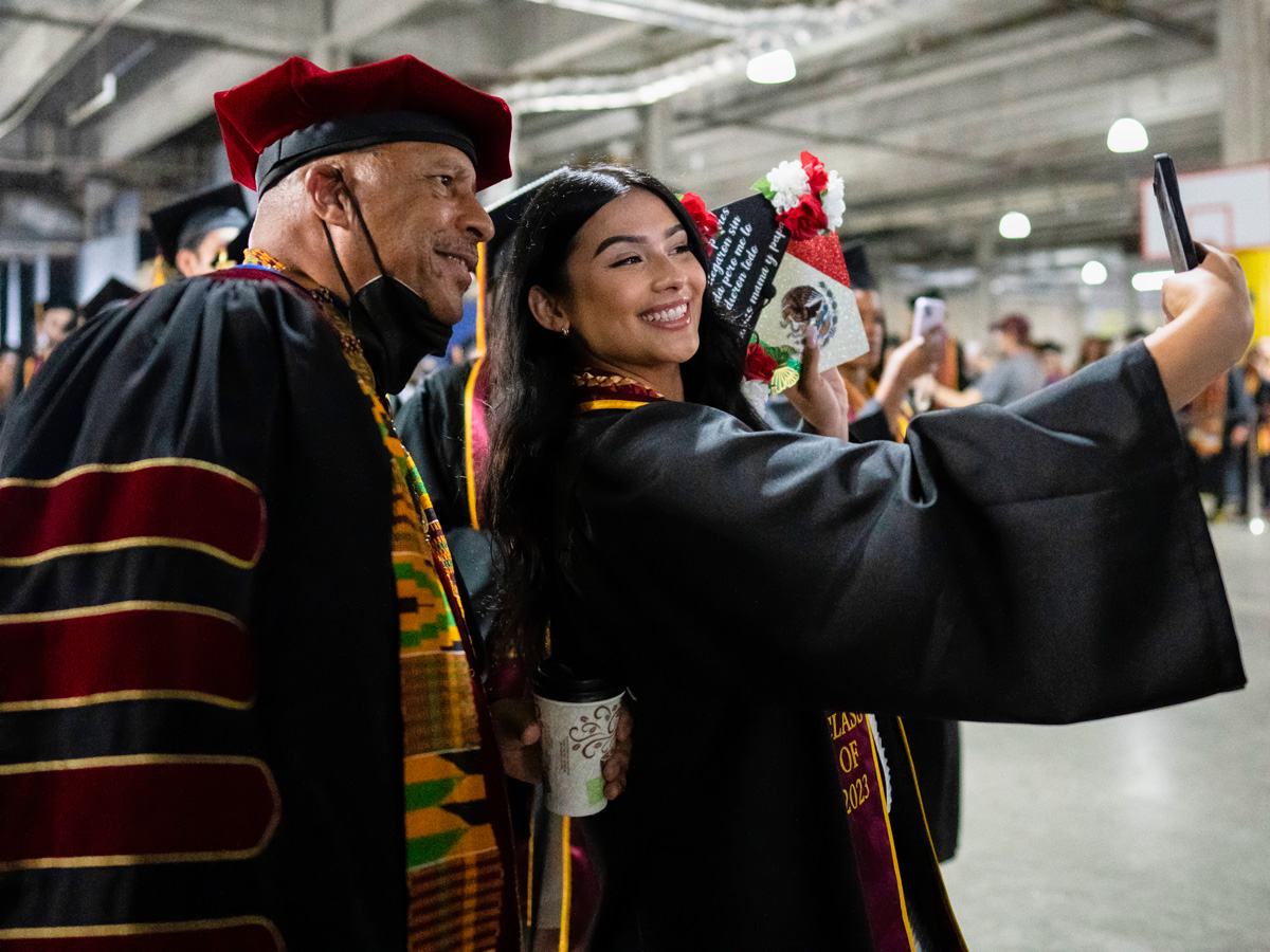 a graduate posing for a selfie with president parham