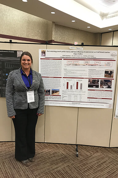 Rebecca Swanson smiling next to a presentation board at a professional event