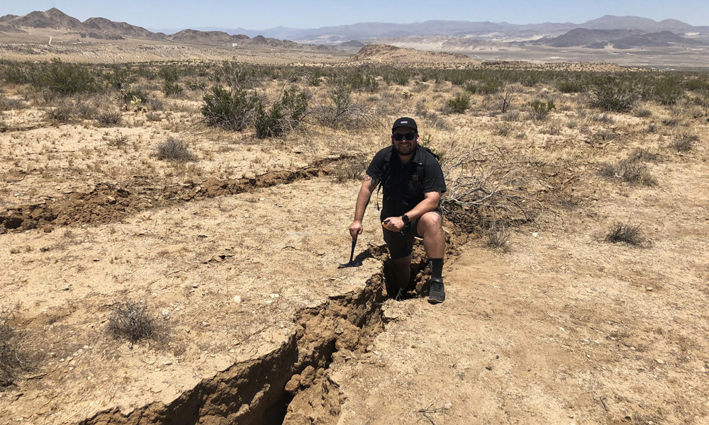 CSUSB alumna Bryan Castillo in the desert studying large crack in the ground
