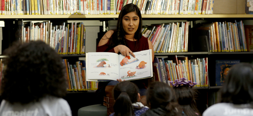 teacher reading a picture book to young students