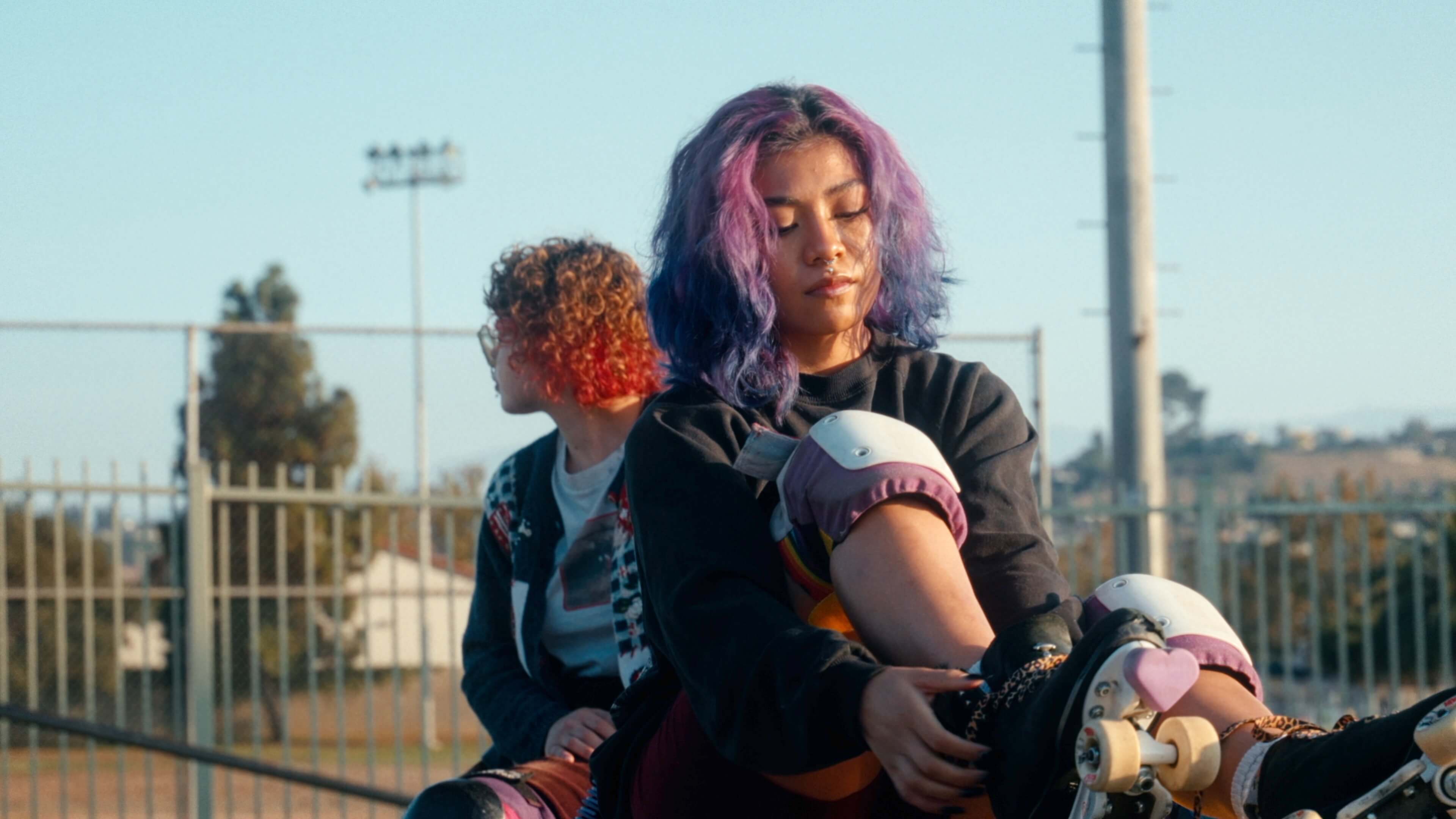 a person with purpl e hair adjusting her skate