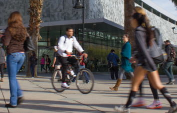 Transfer - Which Campus is Right for You - Man riding bike on campus