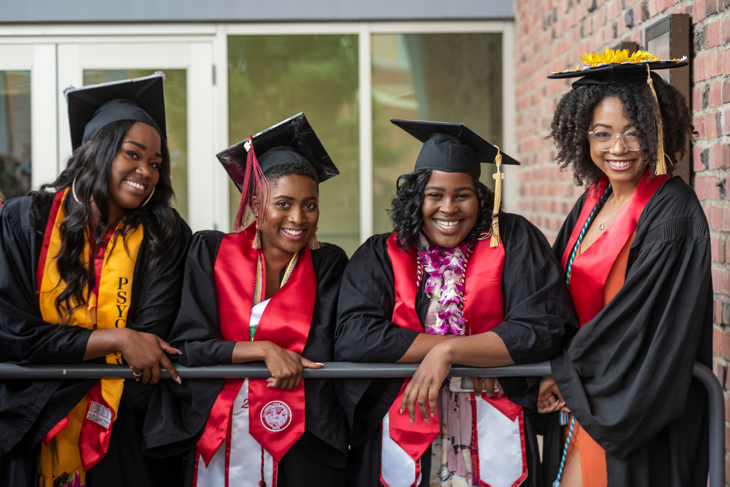 Four girls at a CSU graduation ceremony smiling in their caps and gowns.