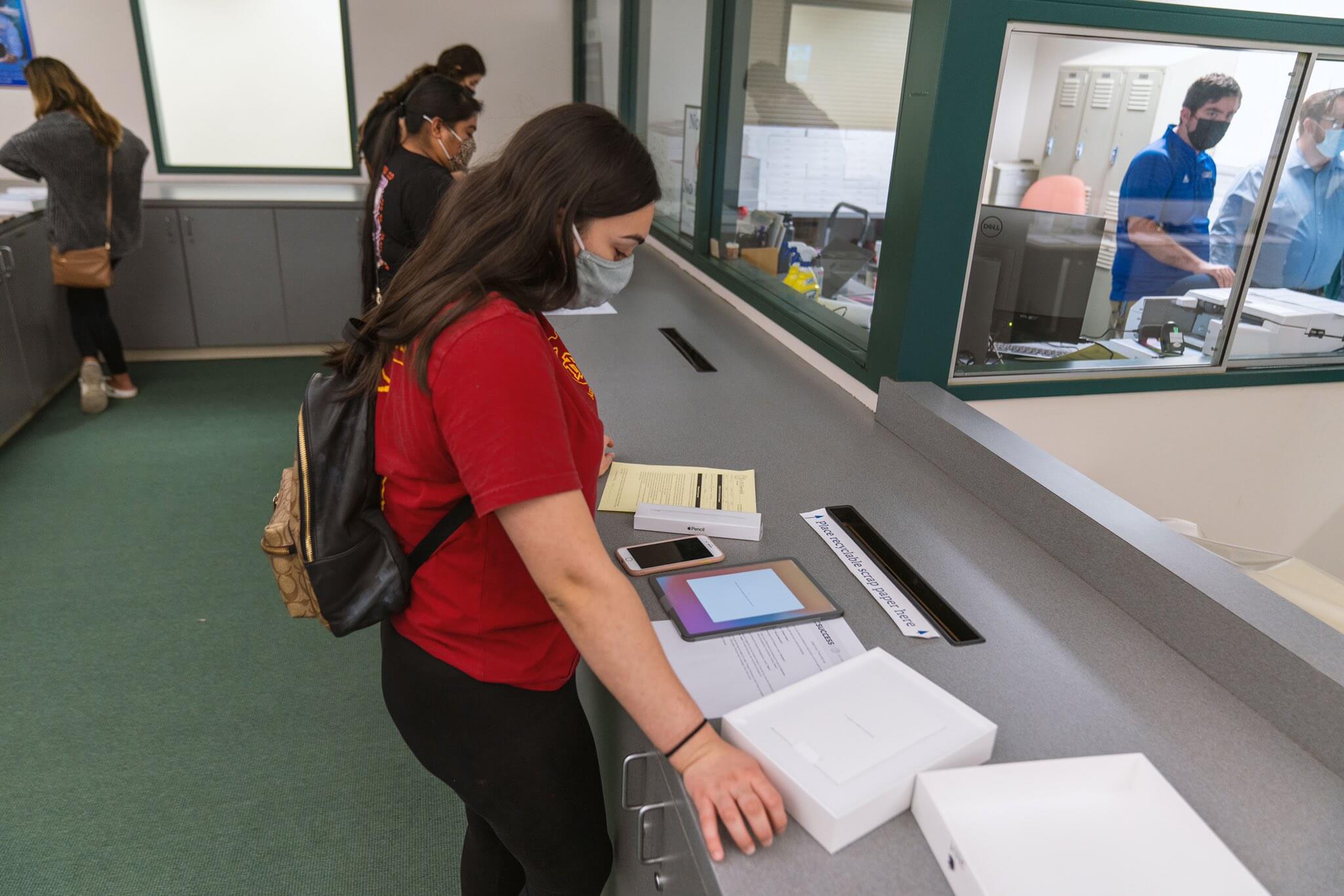 woman wearing backpack stands at counter setting up her new iPad