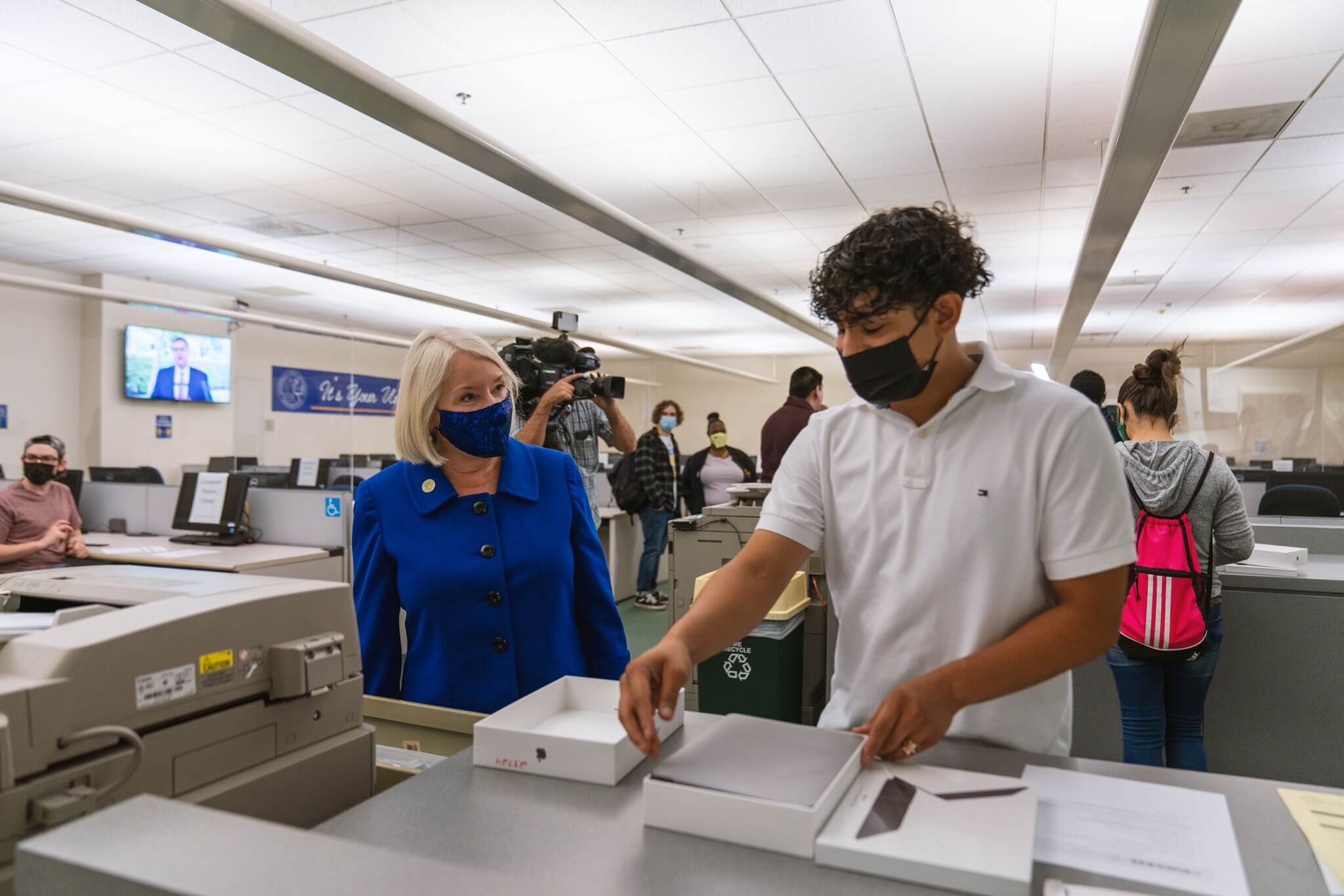 woman in blue sut talks to a student inside an office environment with technology all around