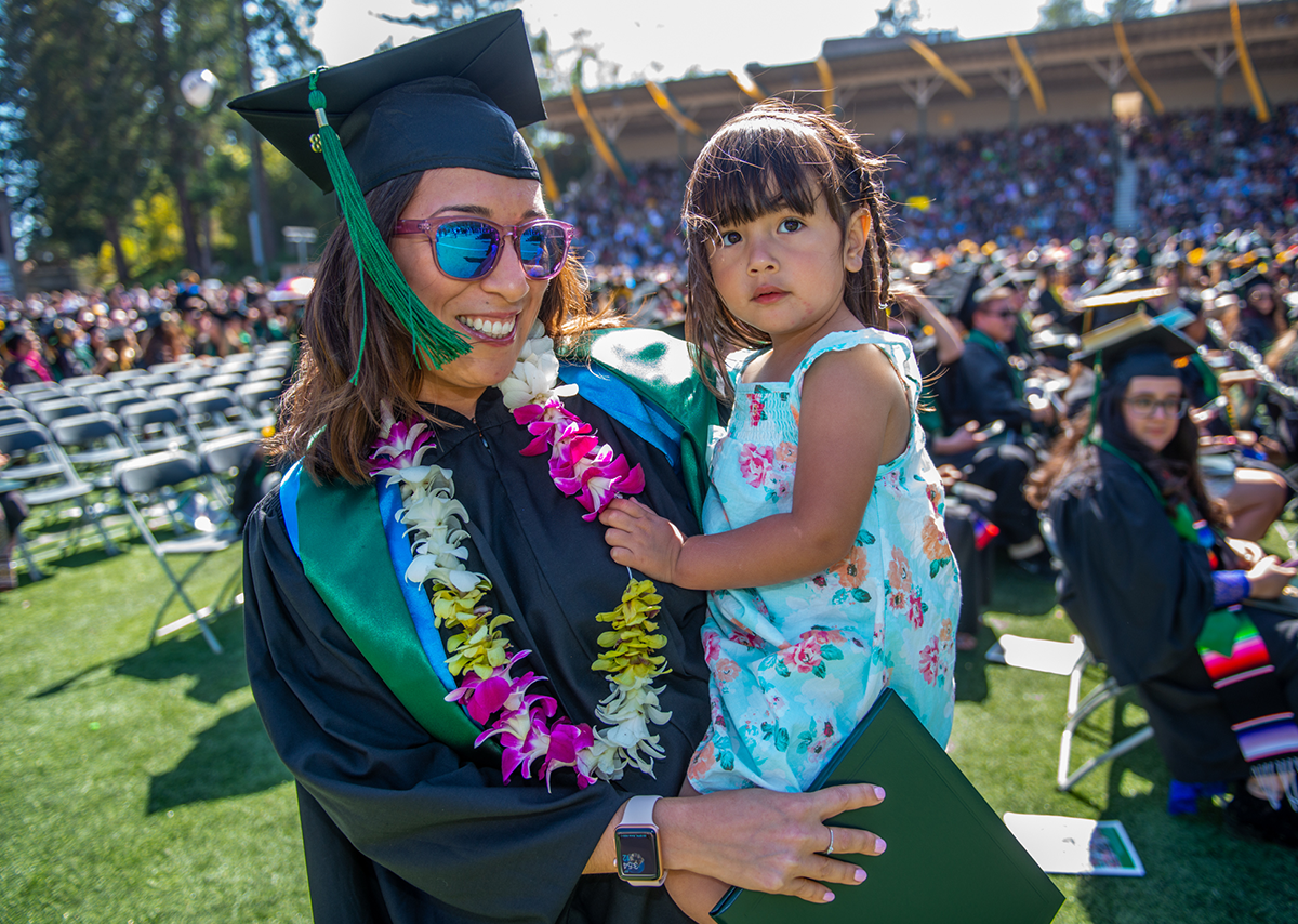 Cal Poly Humboldt student at graduation holding her daughter.