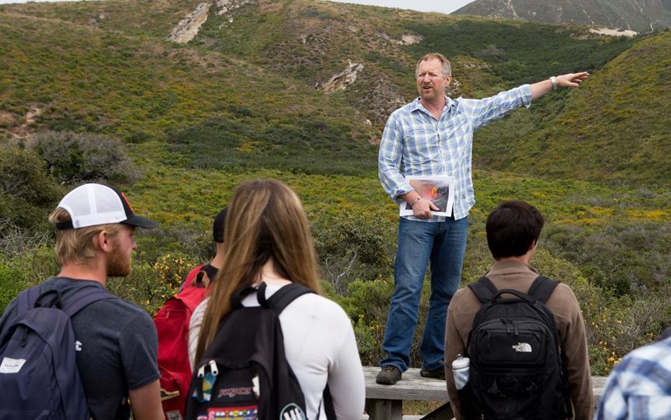 professor pointing to landscape with students outside