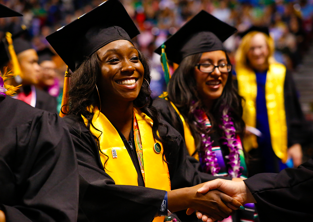 Student shakes hands with faculty member at graduation