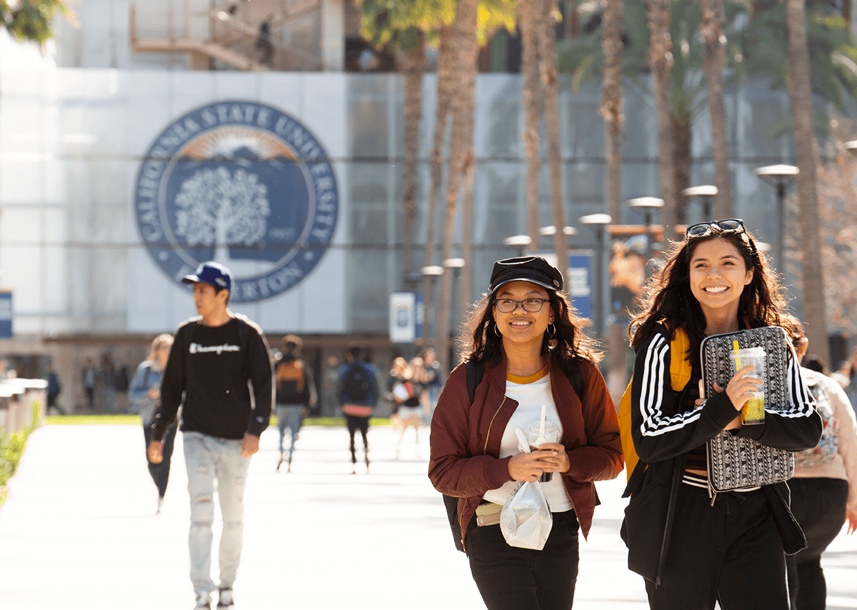 Two female students walking on campus smiling