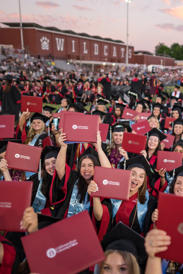 graduating students holding up diplomas