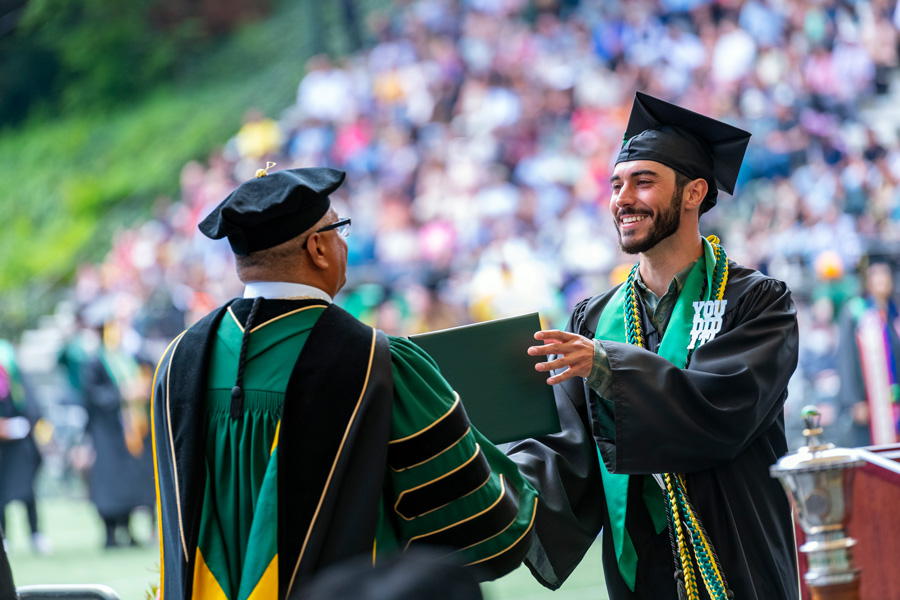 graduating student accepting diploma from campus president