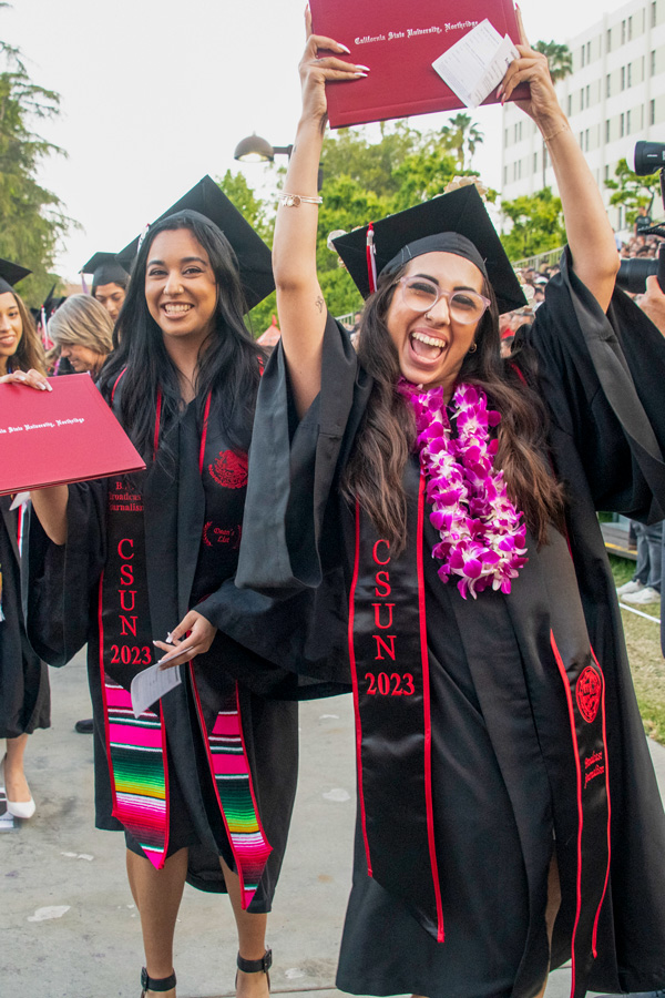 graduating student holding diploma up in celebration