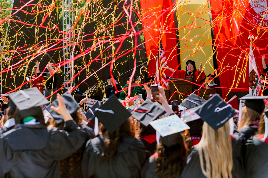 stanislaus state president ellen junn on stage with streamers flying into crowd of graduating students