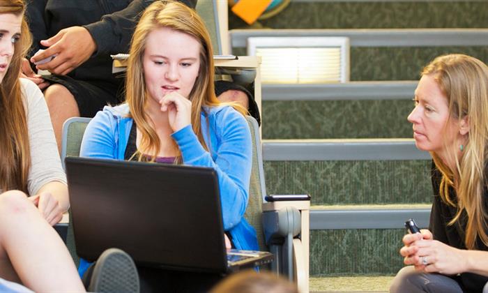 student on her laptop getting help from a professor